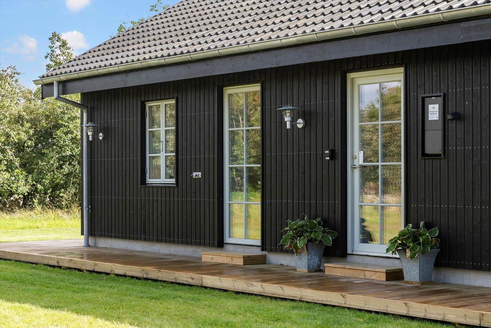 Schwarzes Holzhaus mit Holzterrasse und weißen Fenstern