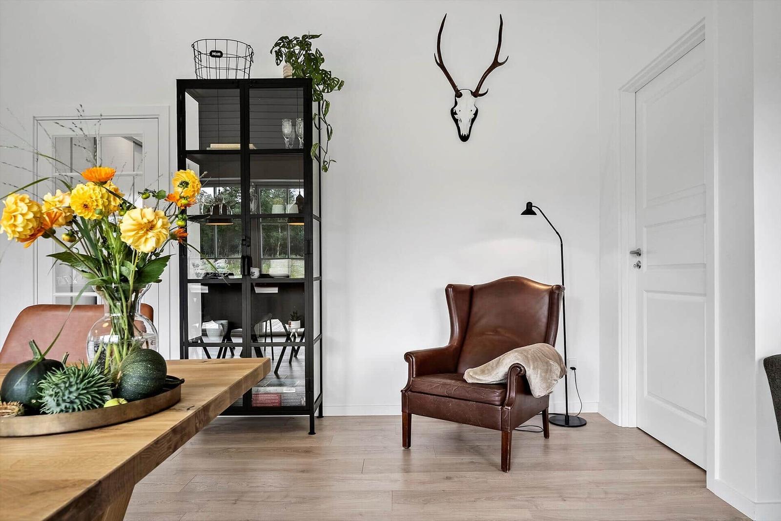 Ein Raum mit braunem Ledersessel, Holzboden und schwarzem Regal.