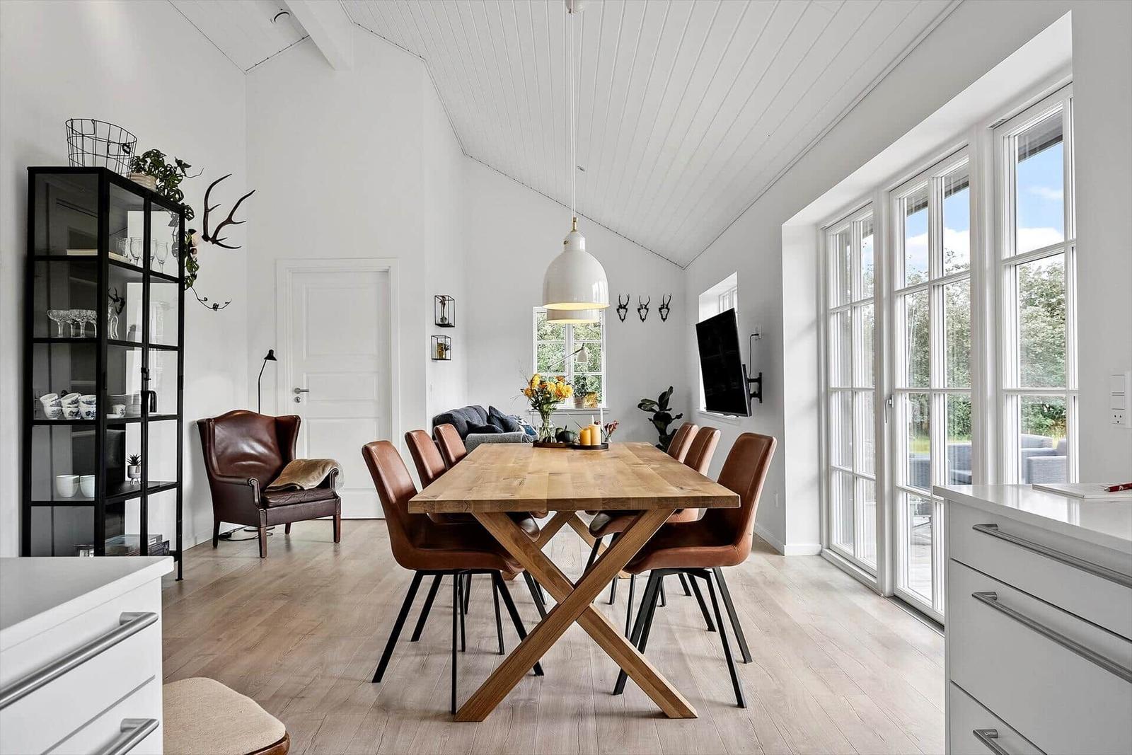 Esszimmer mit Holztisch, braunen Stühlen und großen Fenstern.