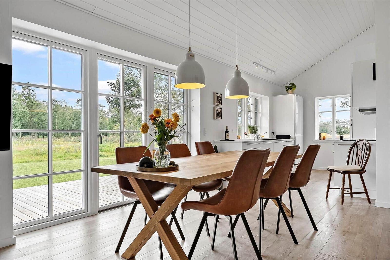 Essbereich mit Holztisch, braunen Stühlen und Blick auf die Terrasse.