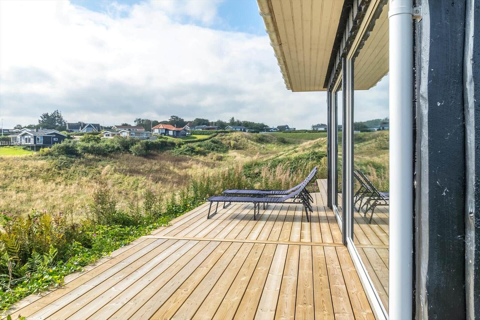 Terrasse mit Liegestühlen und Blick auf die Dünenlandschaft.