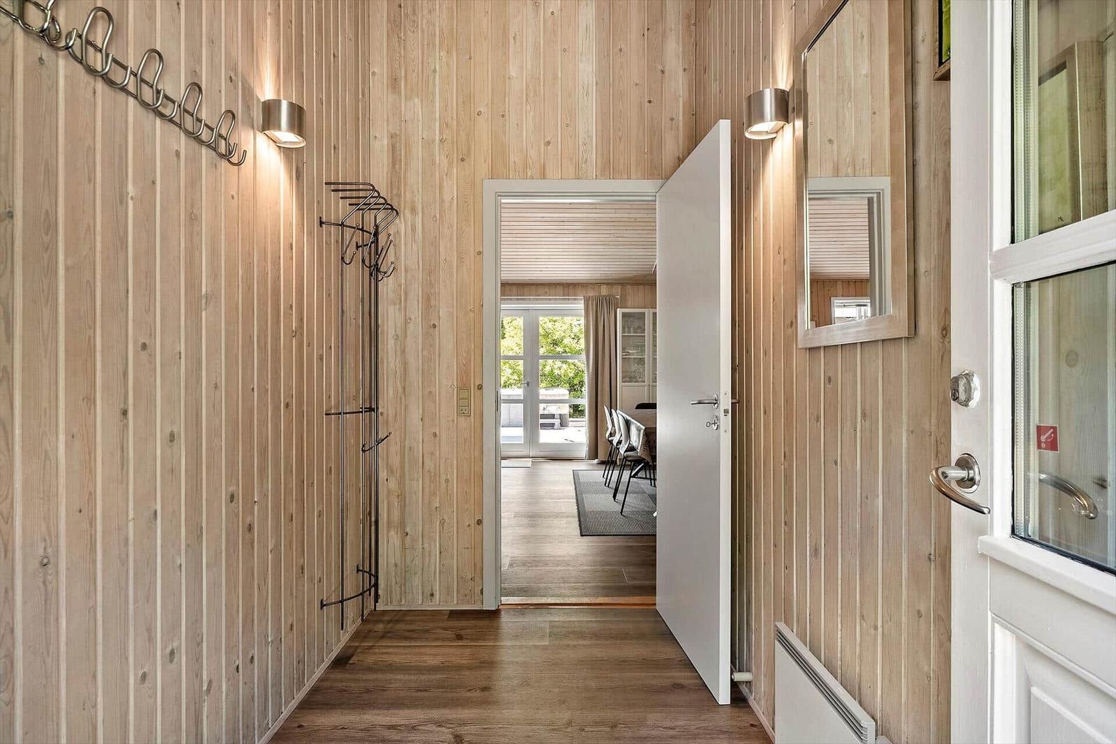 Hausflur mit Holzwand, Garderobe und Blick in Esszimmer.