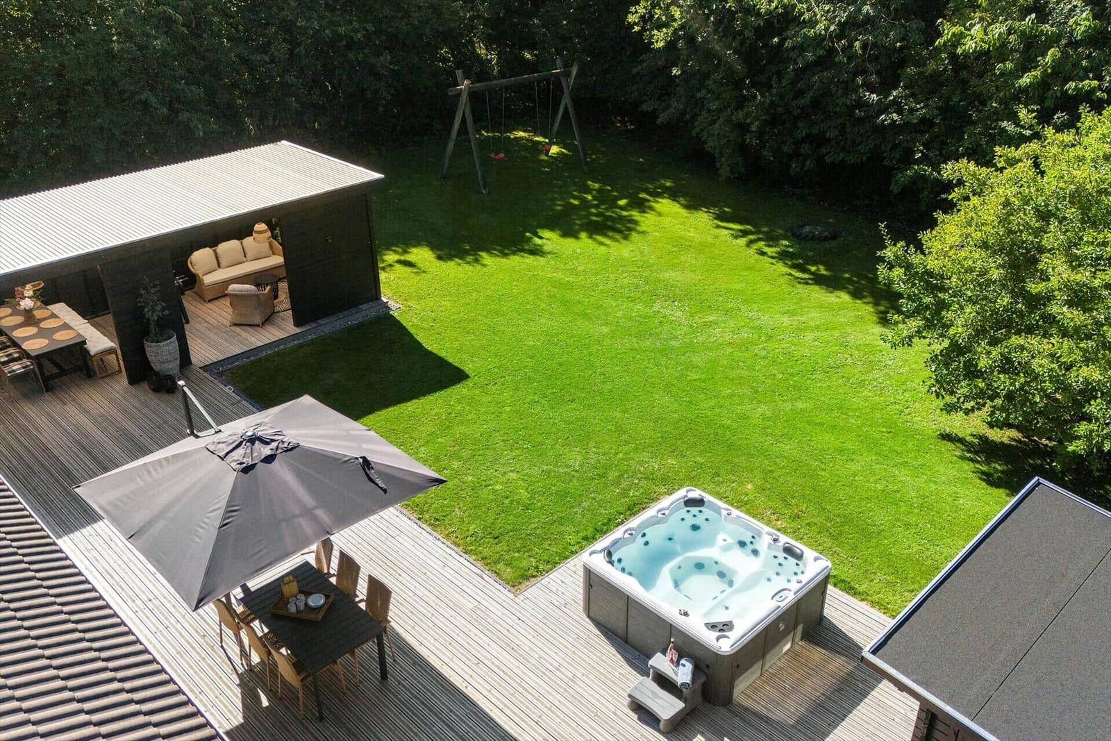 Terrasse mit Whirlpool, Sitzgruppe und Spielplatz im Garten