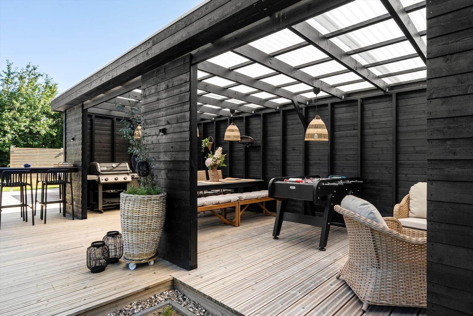 Terrasse mit Grill, Tisch, Stühlen und Fussballtisch unter Dach.