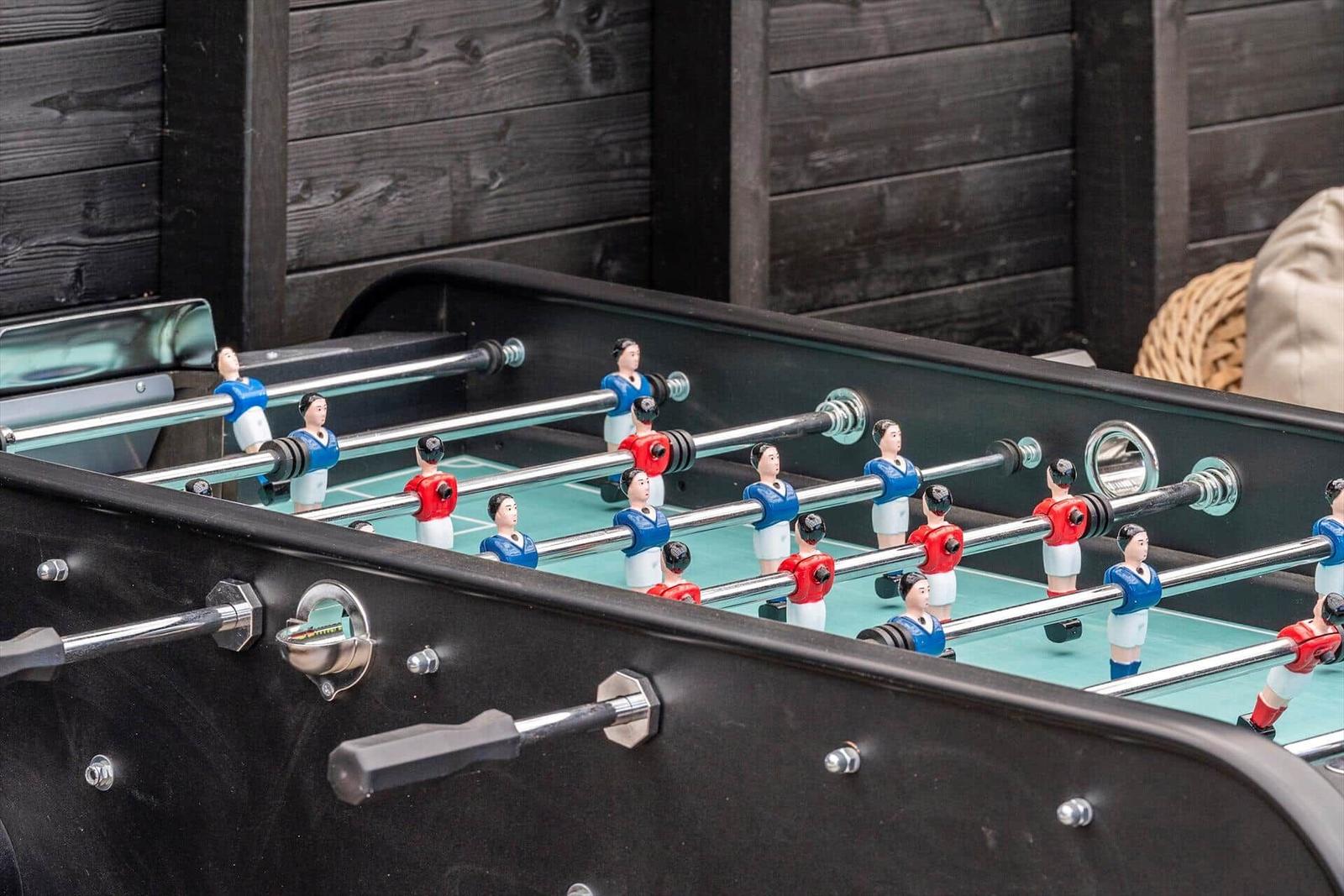 Tischfußballtisch mit roten und blauen Spielern im Freien.