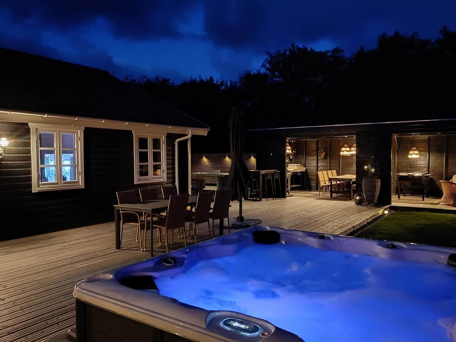 Hochwertiger Außenbereich mit Whirlpool, Terrasse und Grillplatz bei Nacht.