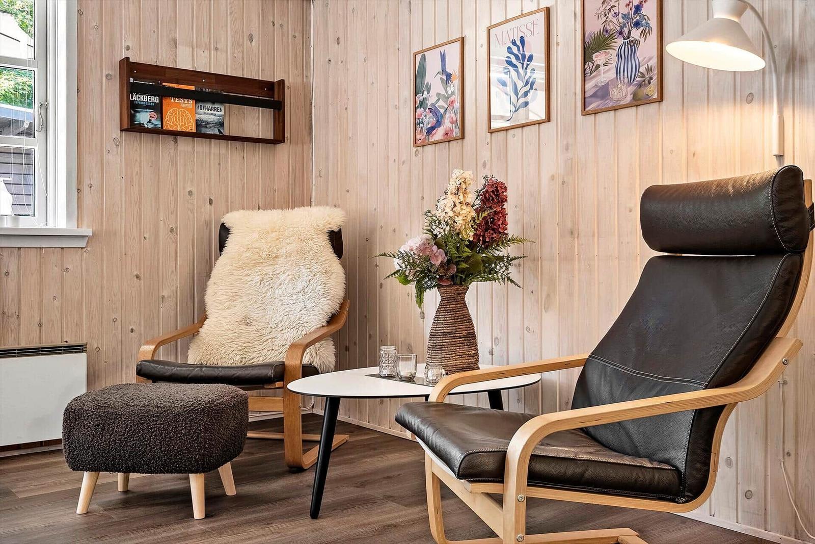 Zwei Sessel mit Felldecke und Beistelltisch in Holzvertäfelung.