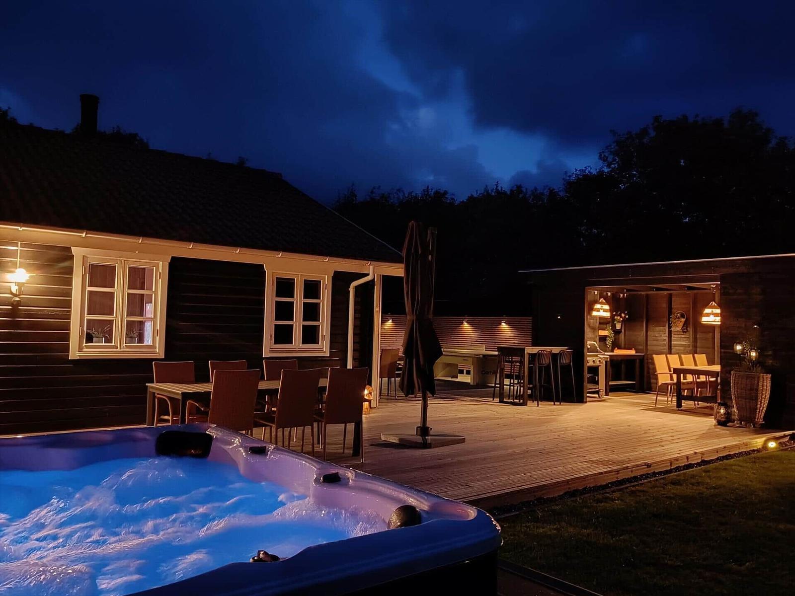 Hochwertige Außenausstattung mit Whirlpool, Grill und Sitzgelegenheiten bei Nacht.