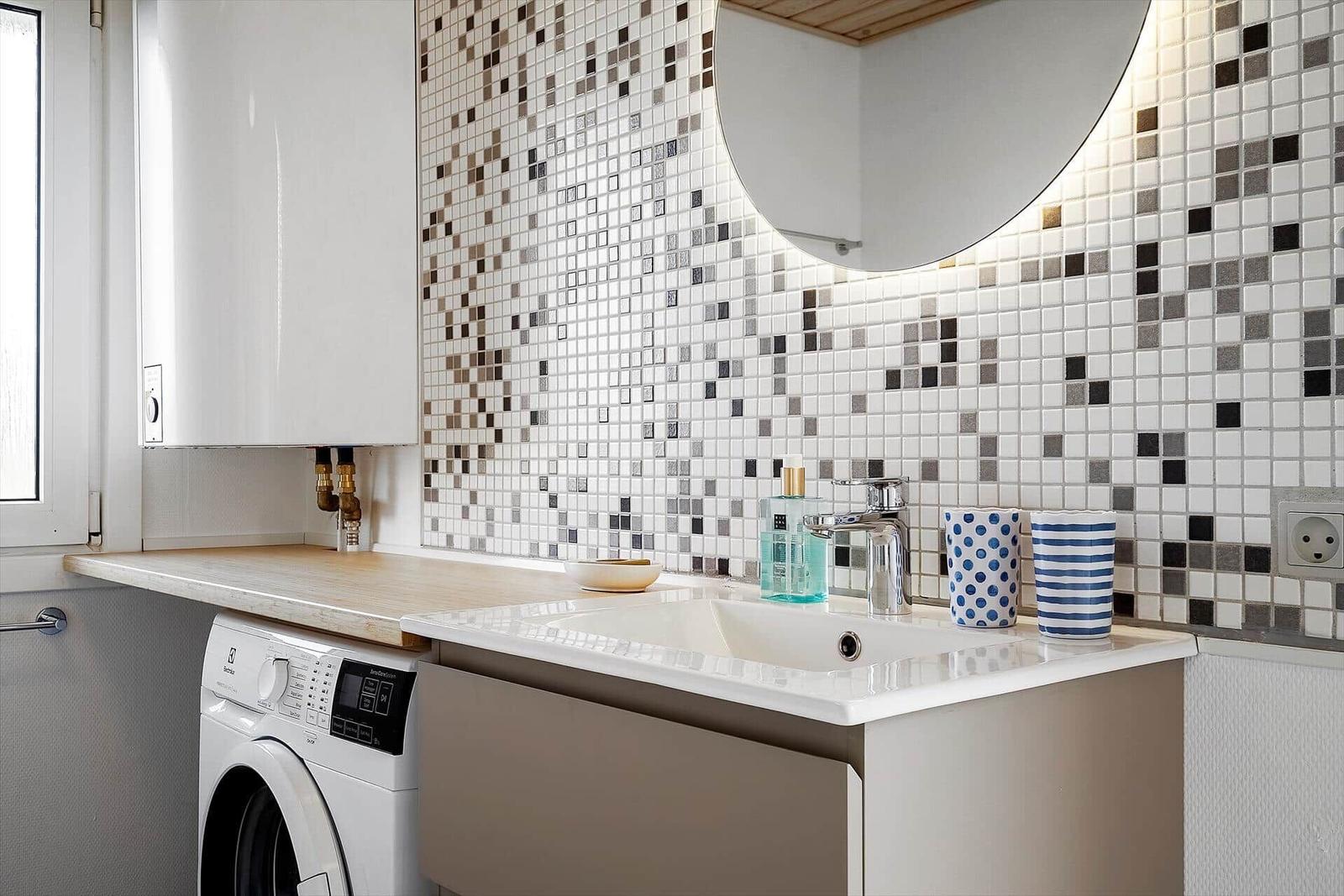 Waschraum mit Spüle, Waschmaschine und Mosaikwand