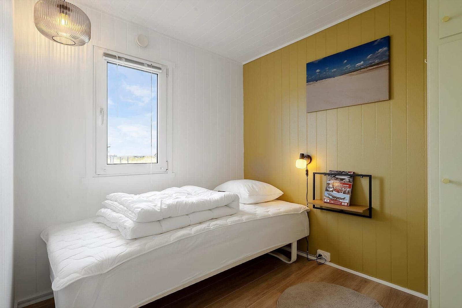Ein Schlafzimmer mit Bett, Fenster und Wandbild.