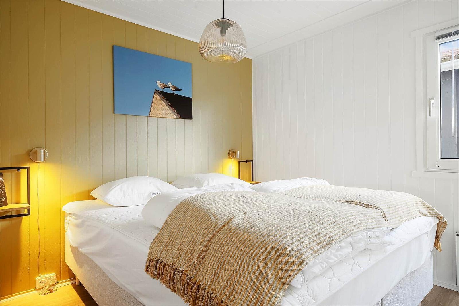 Schlafzimmer mit Bett, Wandbild und Lampe.