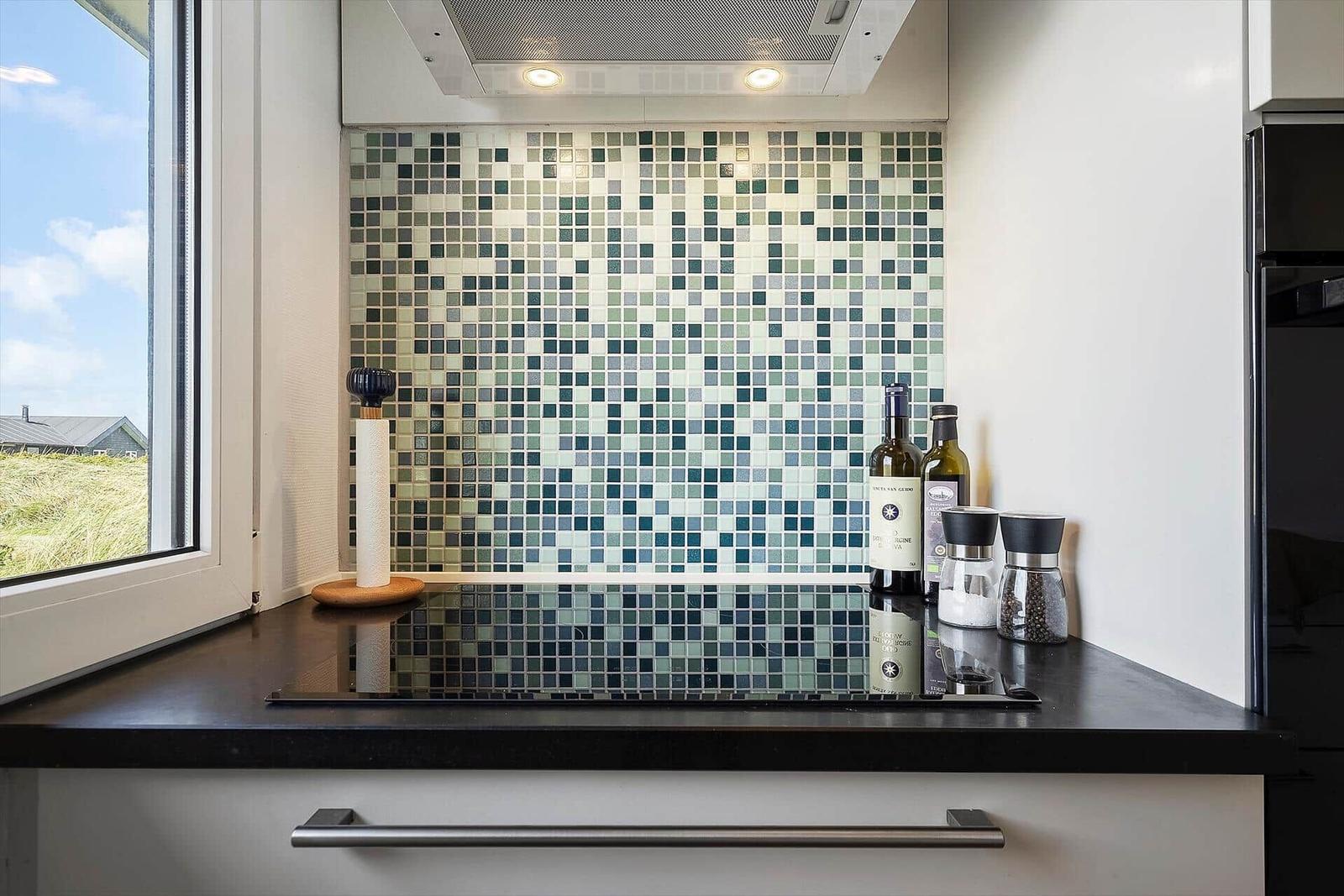Küchenzeile mit Mosaikwand, Fensterblick und Küchenutensilien