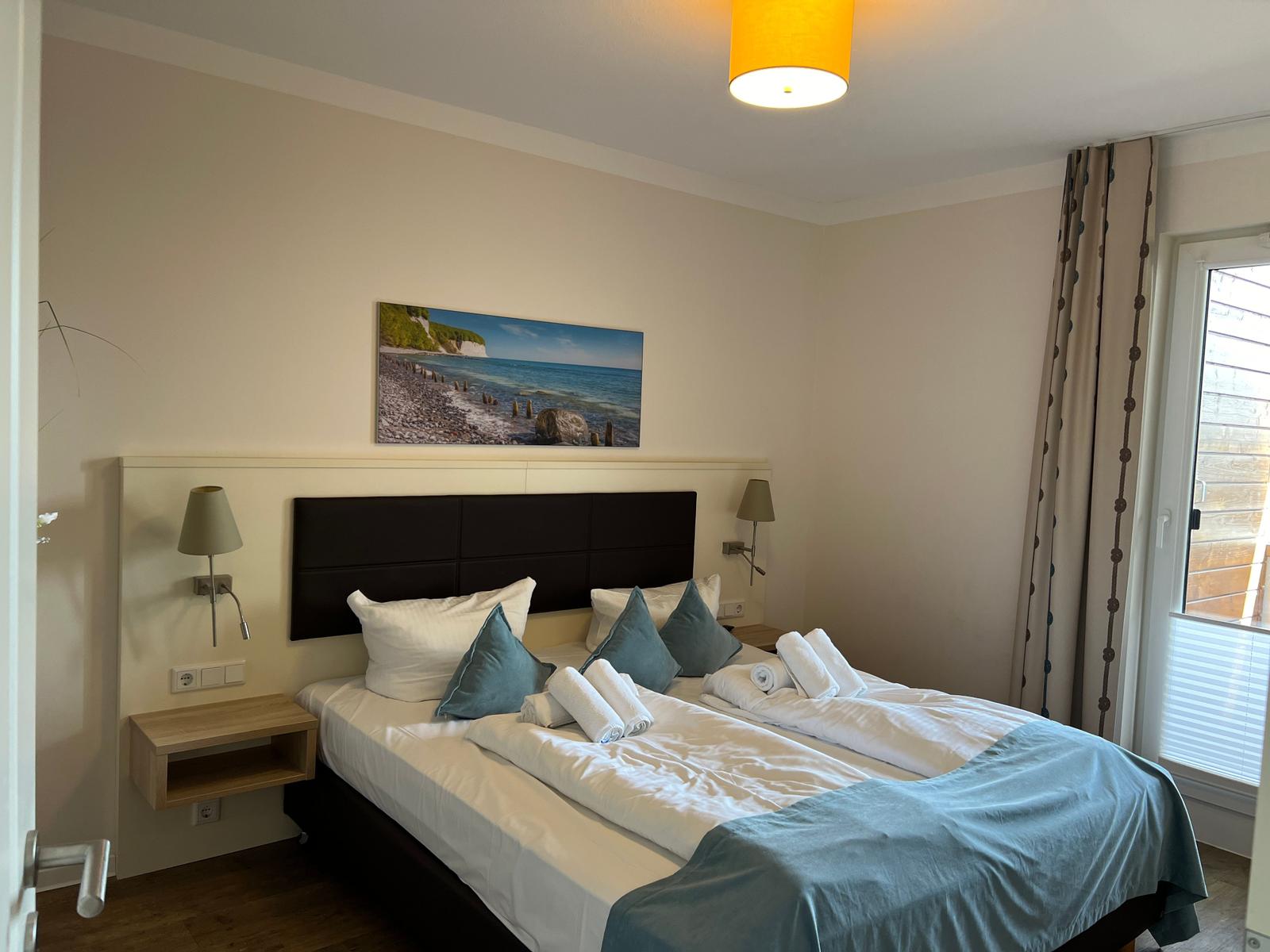 Schlafzimmer mit Bett, Wandbild und Fenster.