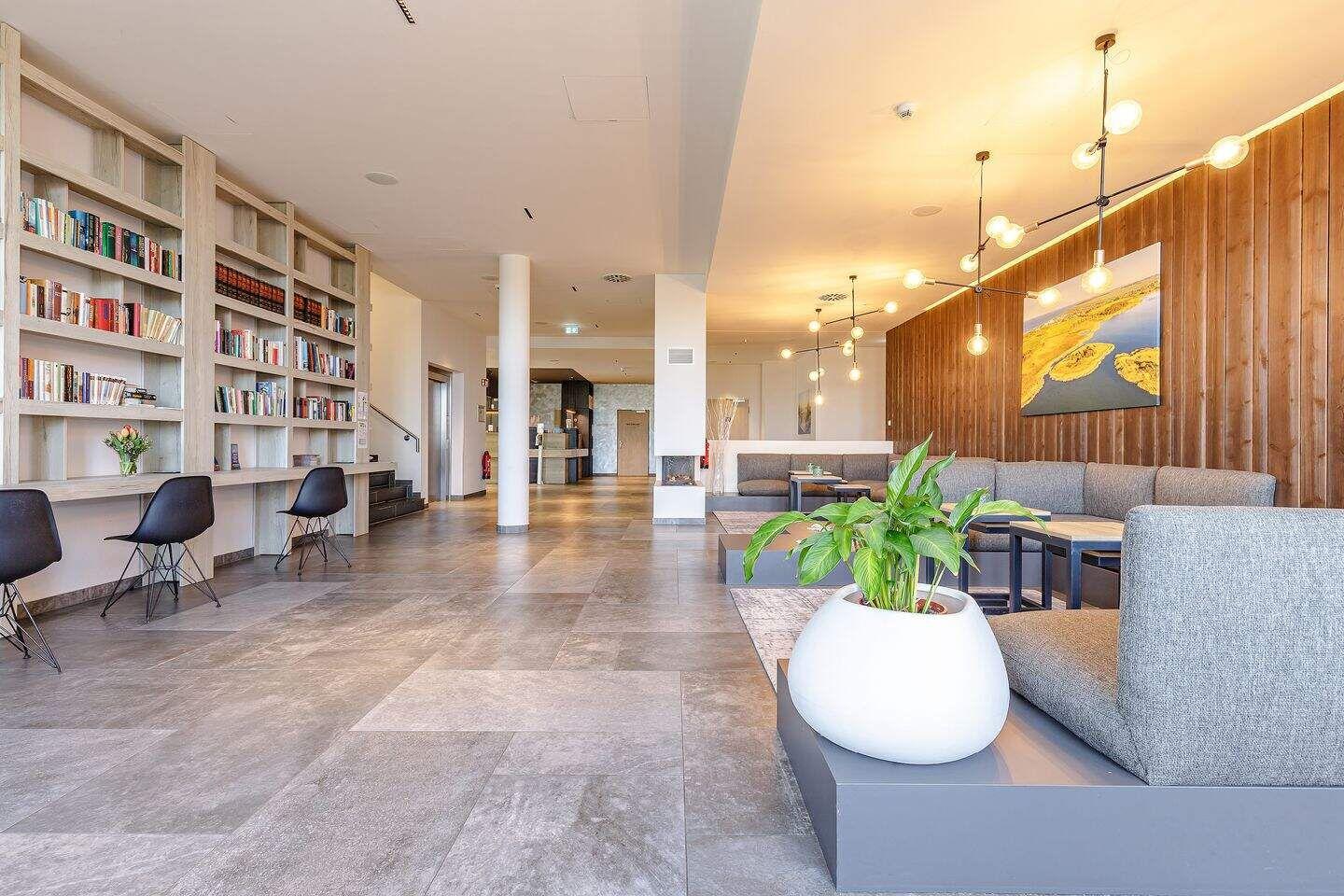 Großer Wohnbereich mit Bücherregalen, Sitzgelegenheiten und Pflanzen.