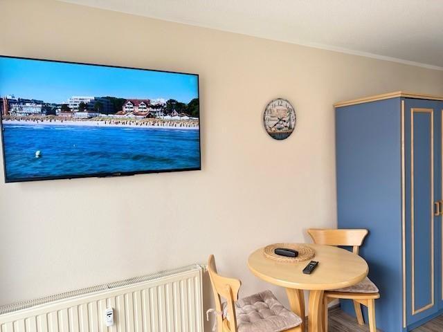 Wohnraum mit TV, runden Tisch und blauem Schrank an der Wand.