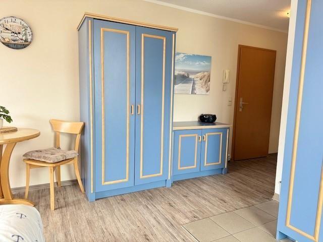 Schlafzimmer mit blauem Schrank und Holzfußboden