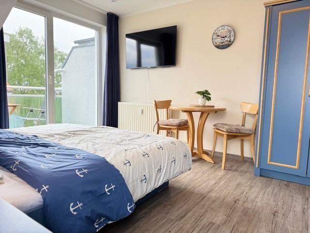 Schlafzimmer mit Bett, TV, Tisch und Stühlen sowie Balkontür.