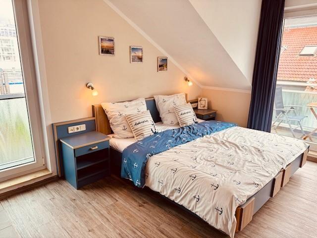 Schlafzimmer mit Dachschrägen, Bett mit Ankern, Nachttische und Balkonansicht.