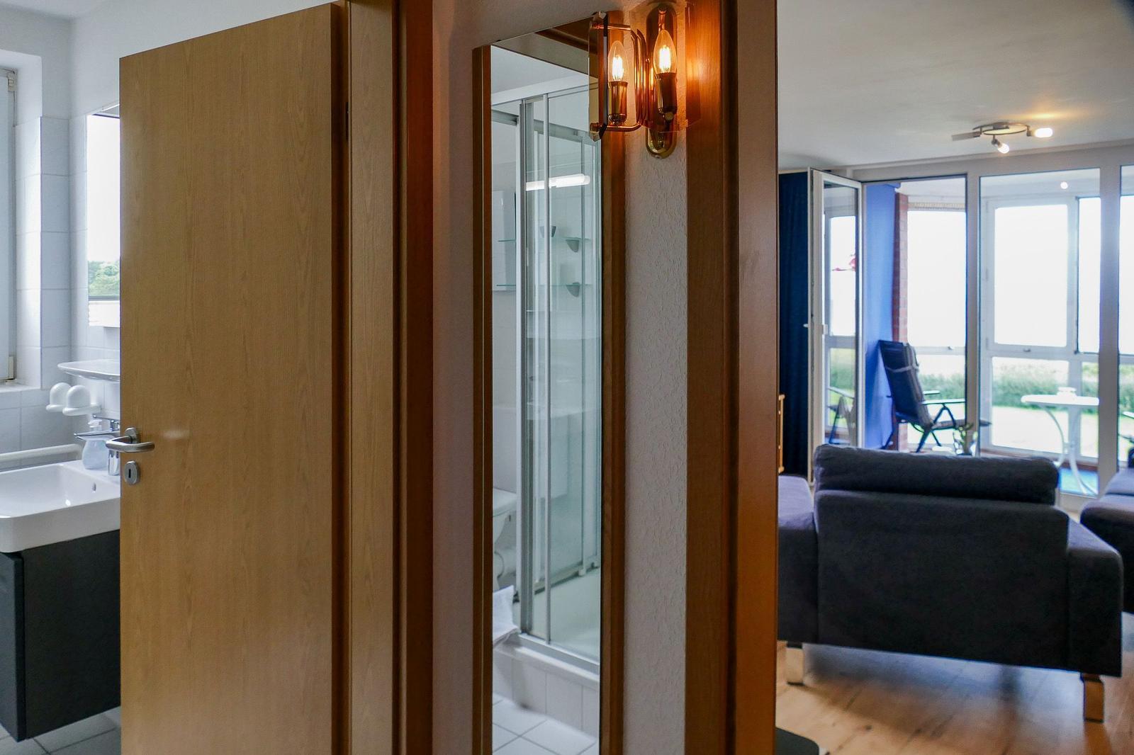 Bathroom with shower, living area with sofa and terrace