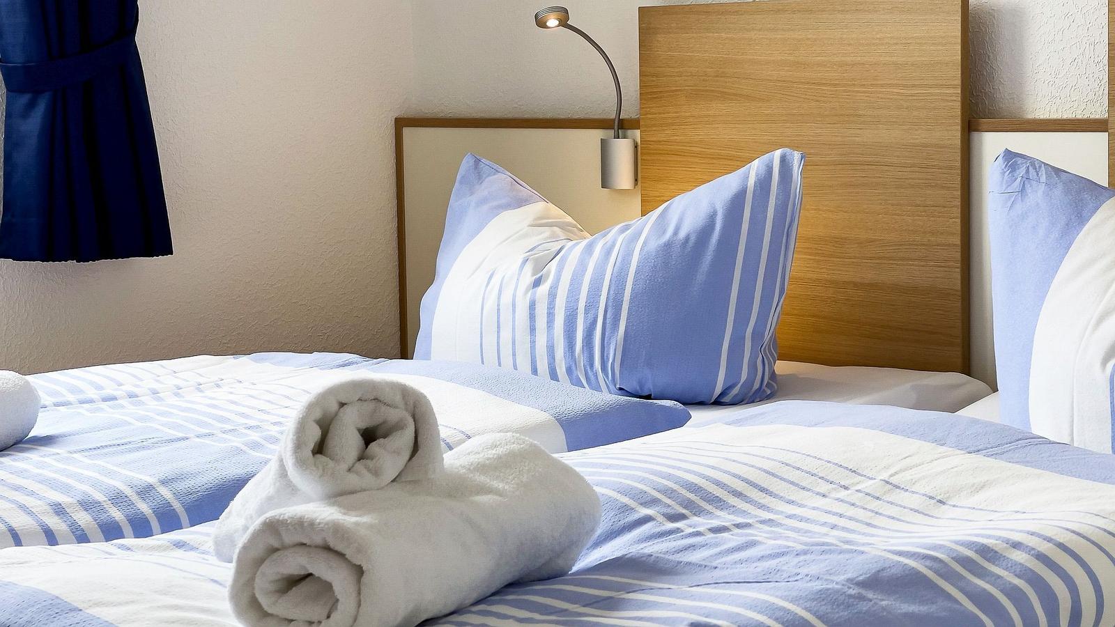 Room with bed, pillows, and rolled towels