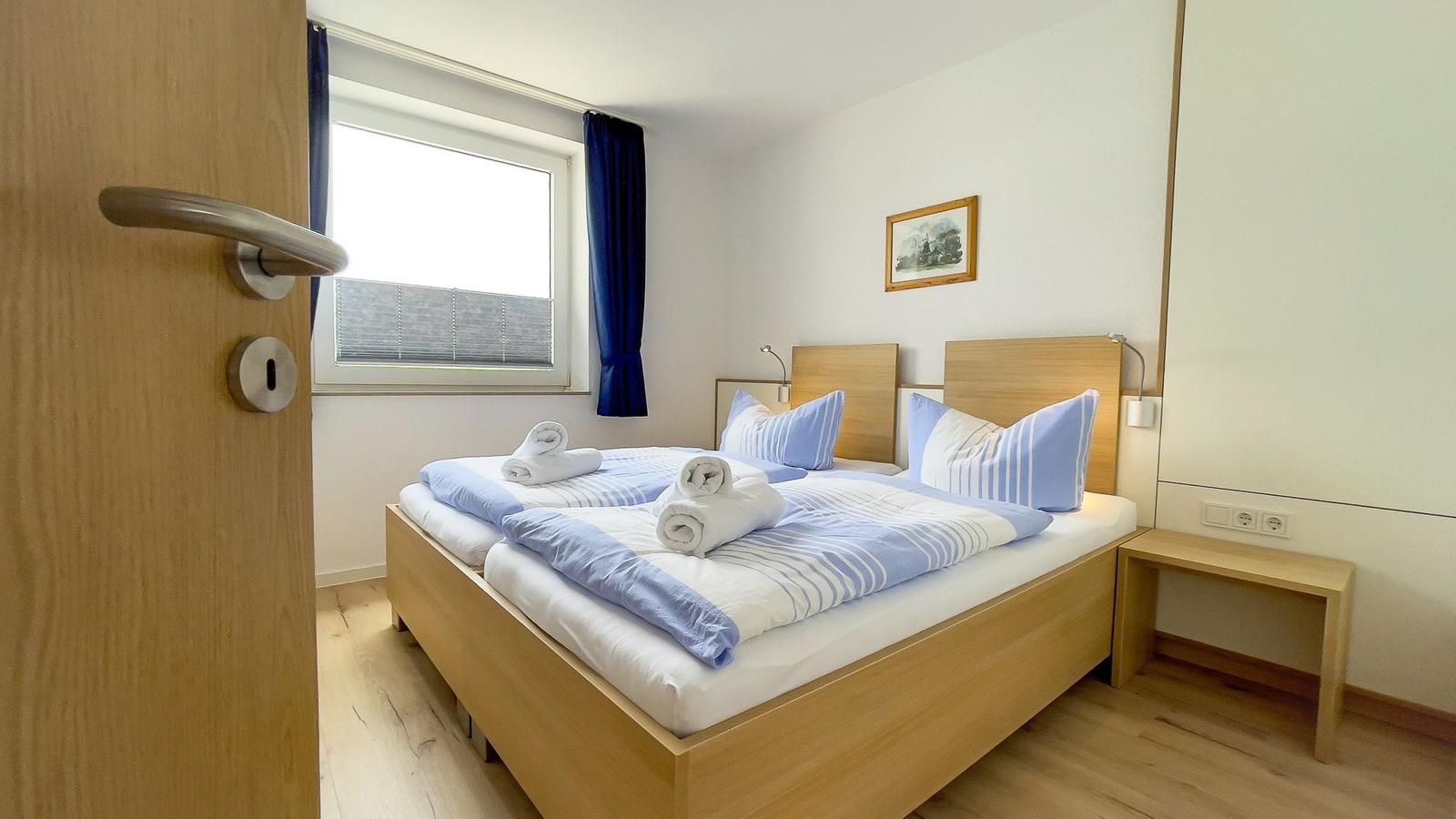 Bedroom with double bed, window, and wooden furniture
