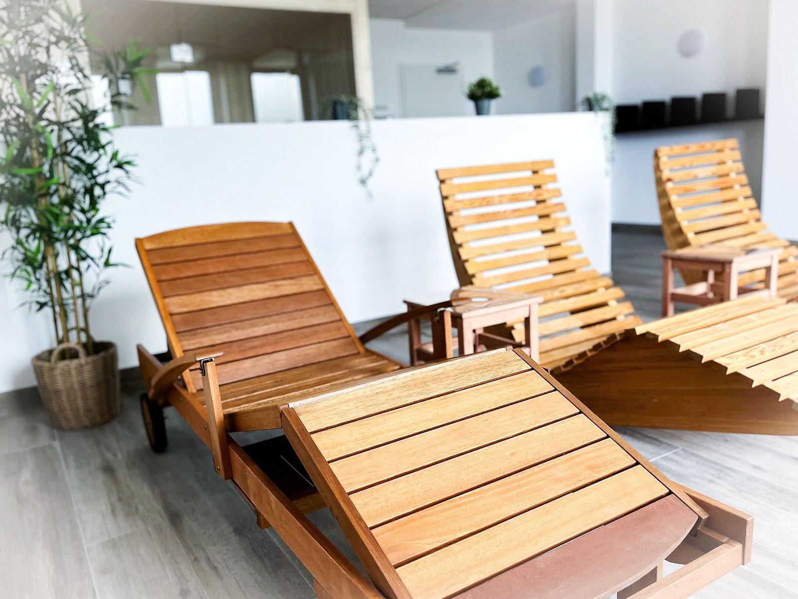 Wooden loungers and plants indoors.
