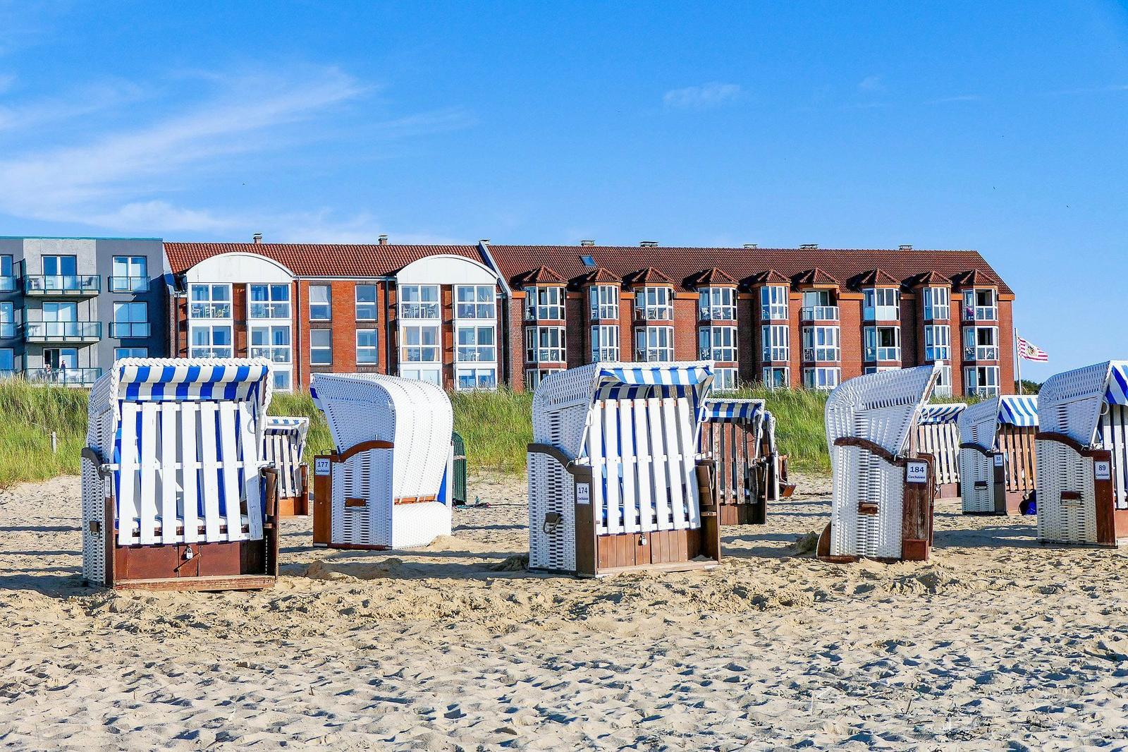 Beach with beach chairs and sea view of vacation apartments.