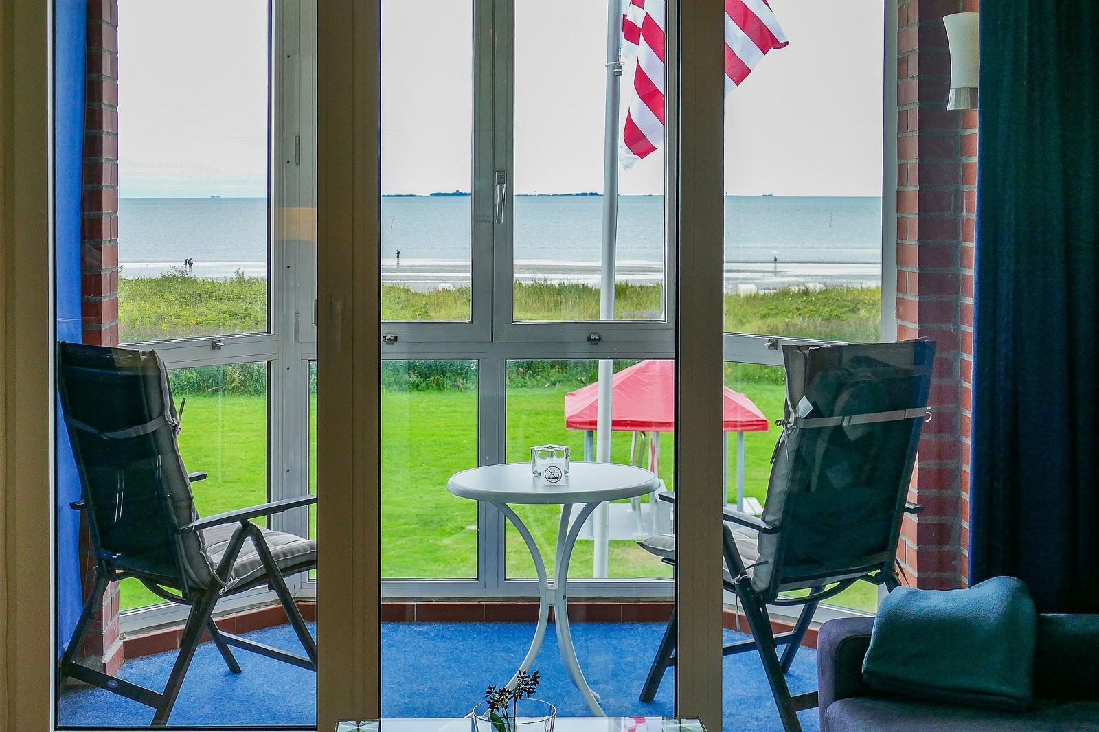 Terrace with two chairs and table, view of beach and sea.