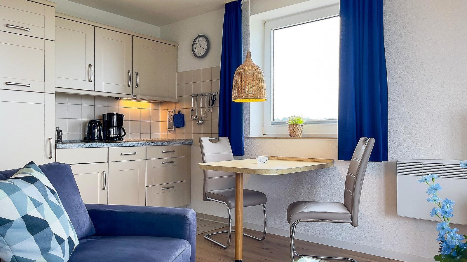 Kitchen with dining area, blue curtains, and window view.
