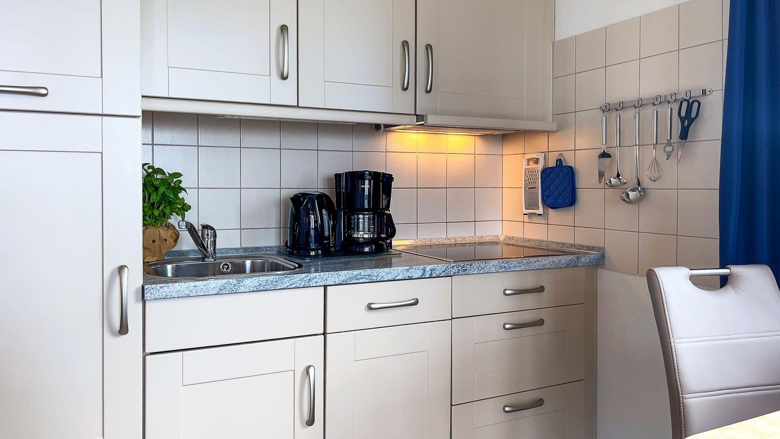 Kitchen with countertop, sink, coffee maker, and kitchen utensils.