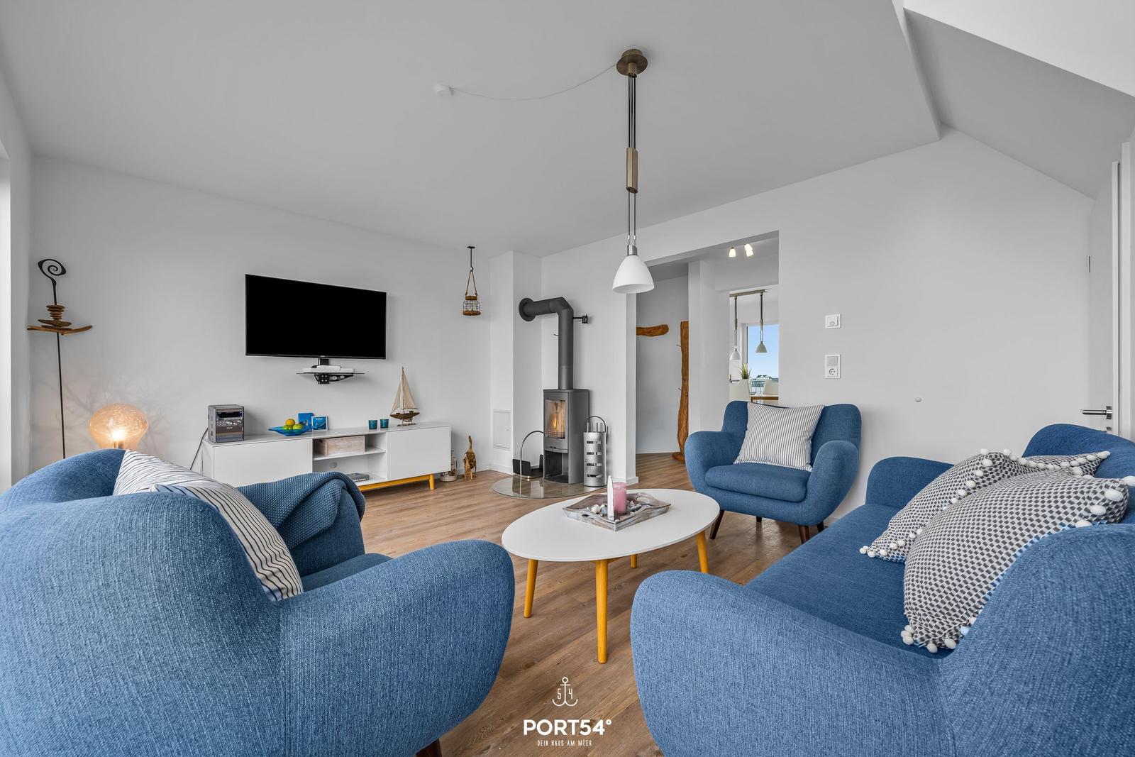 Wohnzimmer mit blauen Sesseln, Kamin und Fernseher an der Wand.