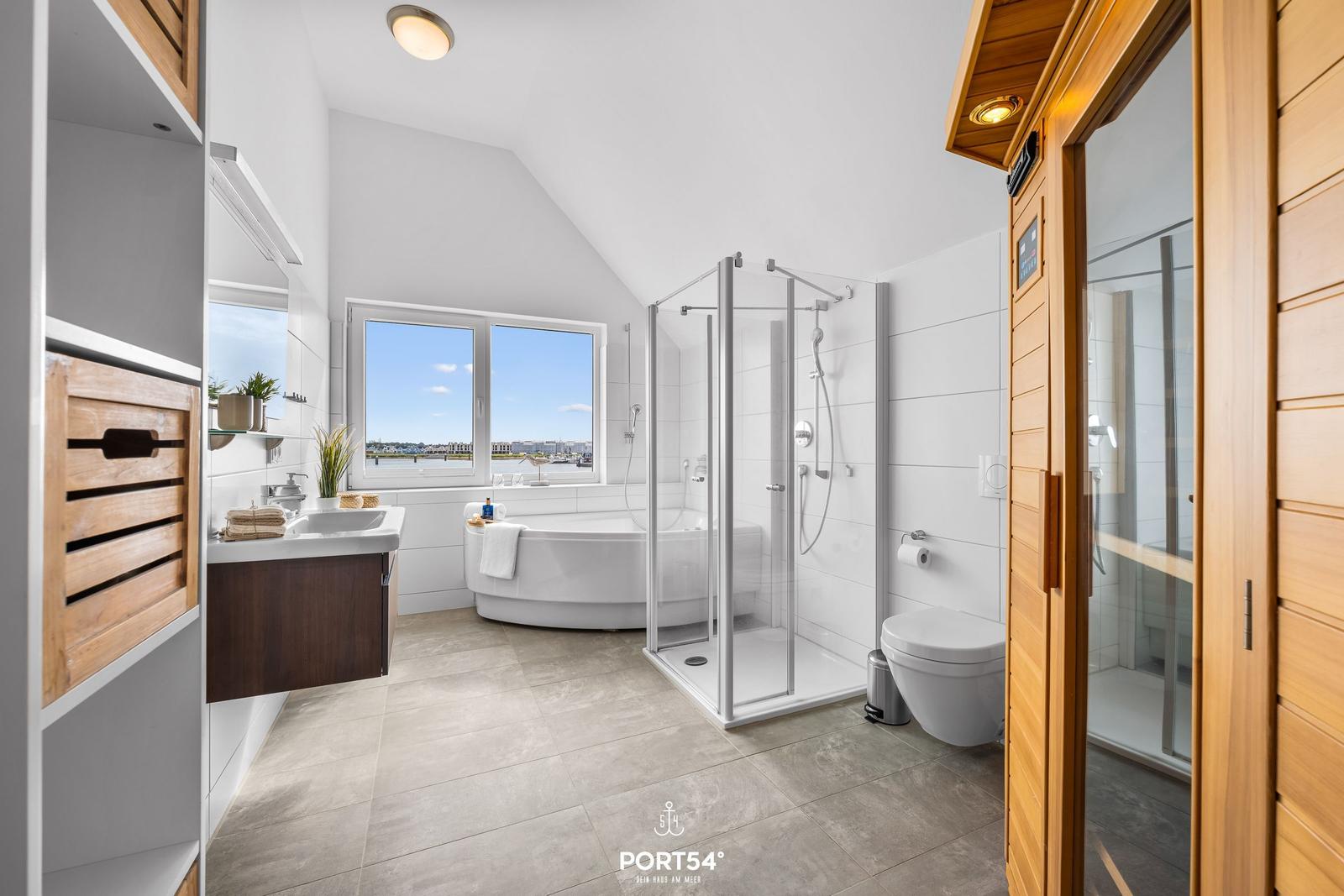 Badezimmer mit Badewanne, Dusche und Sauna. Fenster mit Blick auf Wasser.
