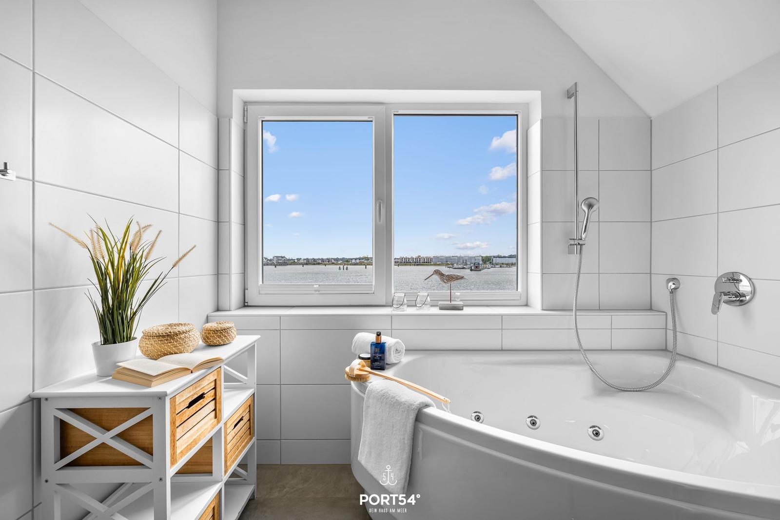Badezimmer mit Badewanne und Blick auf Wasser