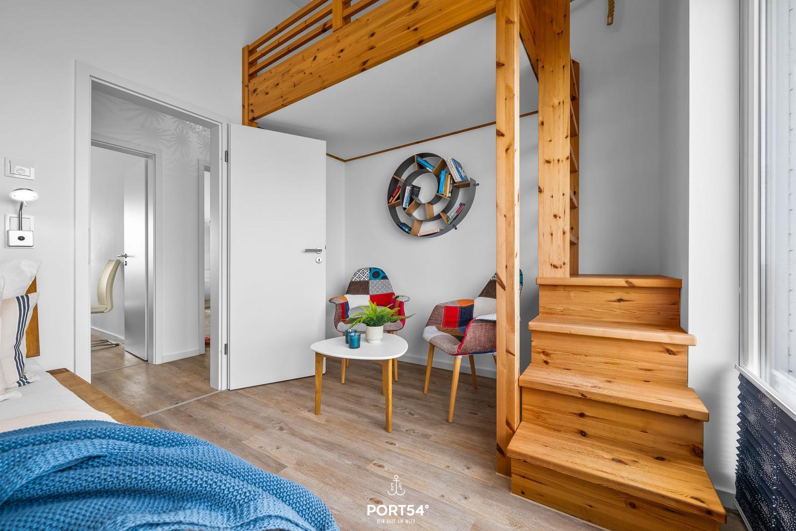 Höhlenwohnung mit Holztreppe, Sitzbereich und Bücherregal.