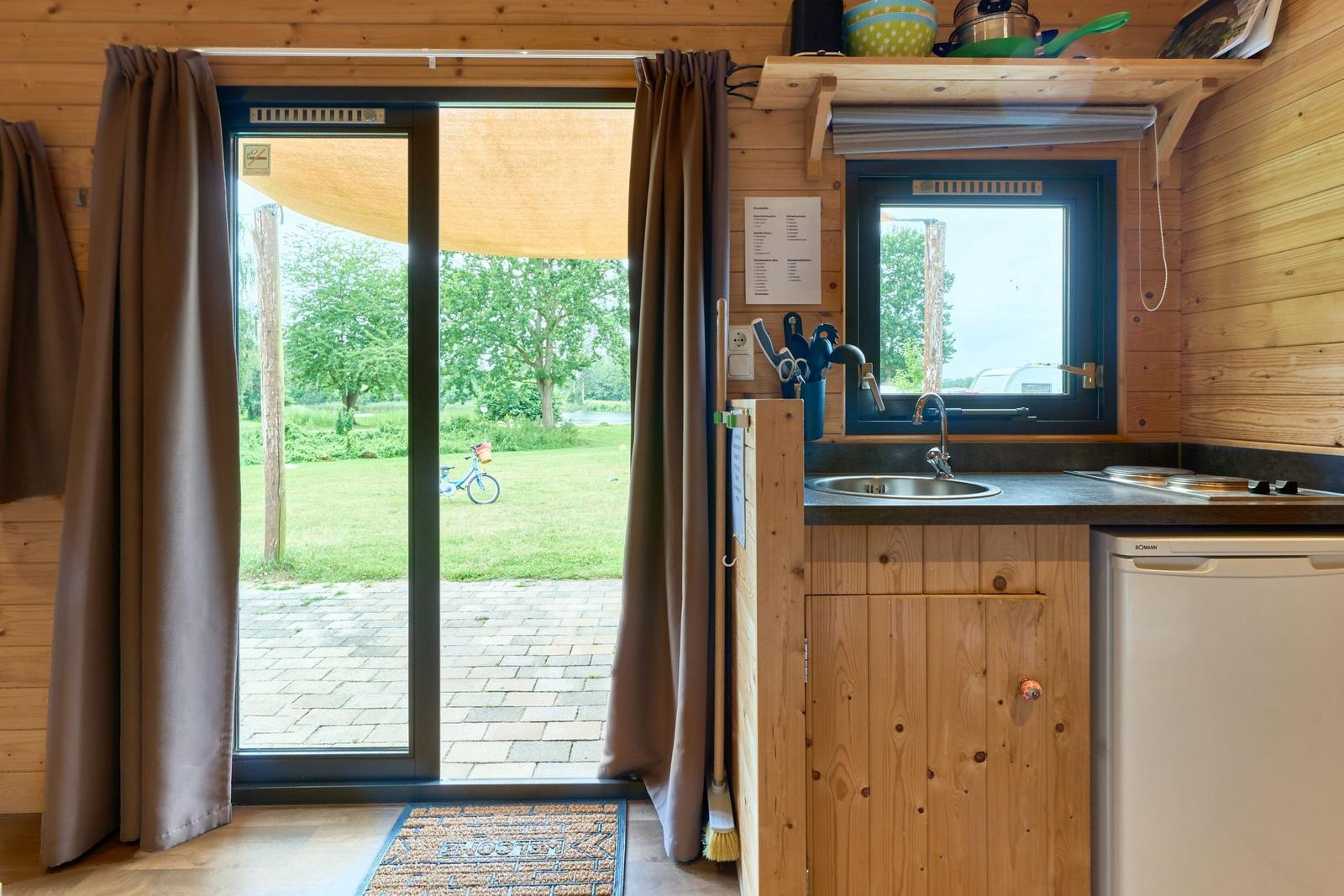 Küche mit Fenster und Glastür zum Garten. Holzwände und Küchenschränke.