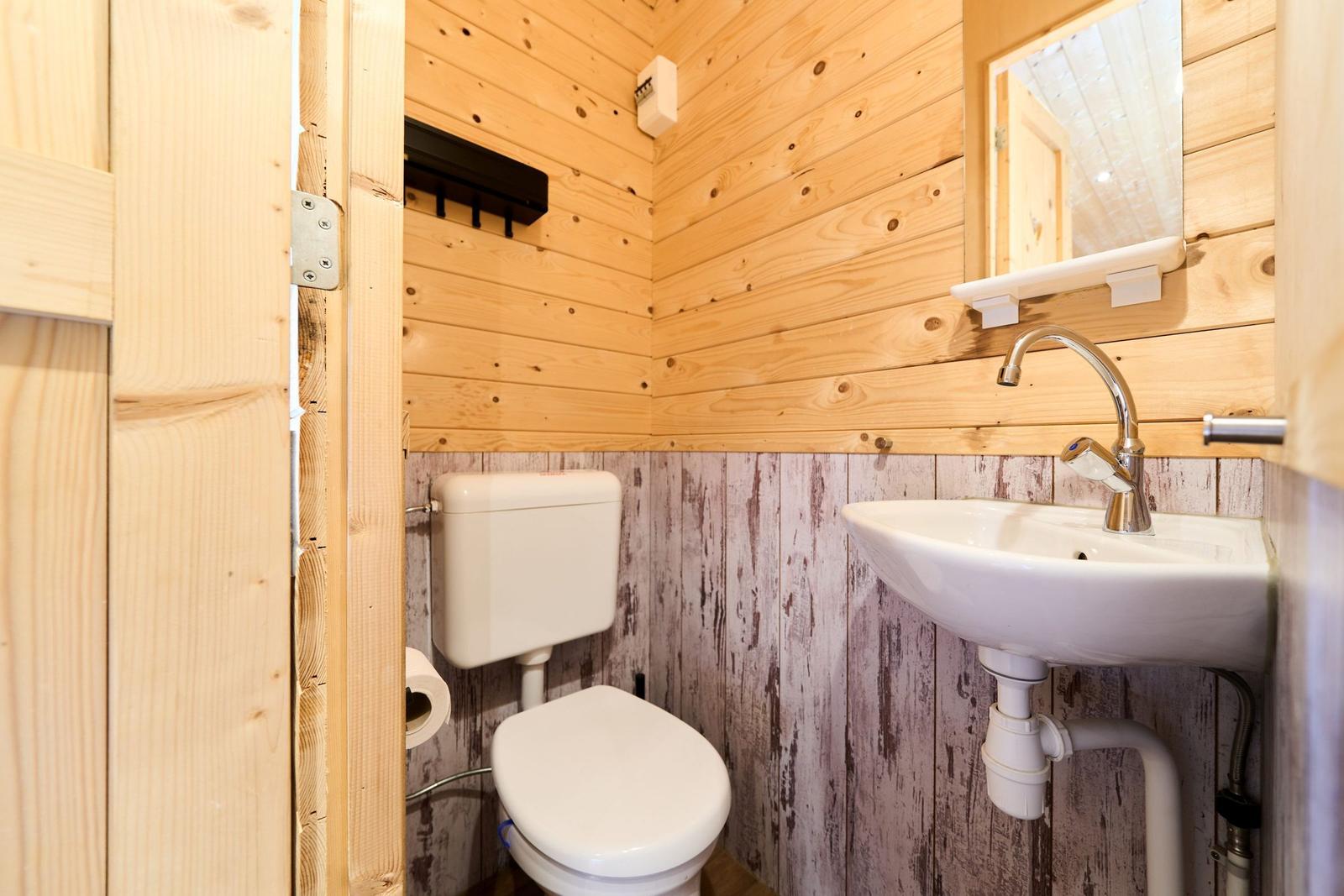 Bad mit Toilette und Waschbecken, Holzwände und Spiegel.