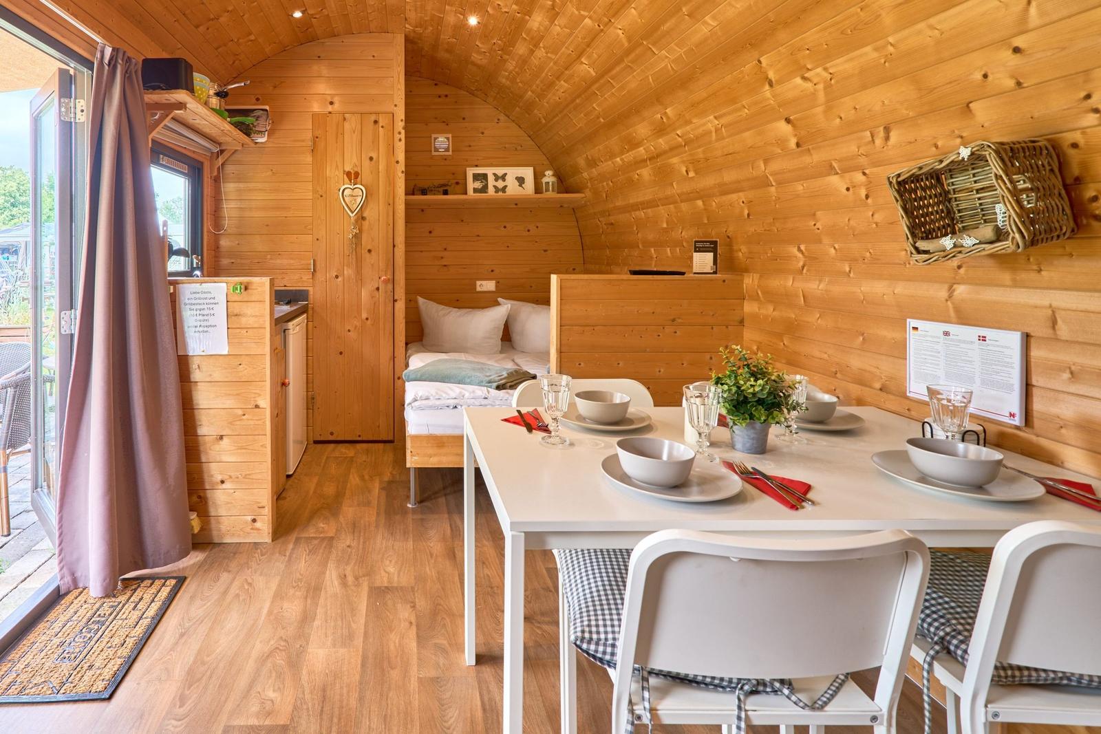 Wohnraum mit Esstisch, Bett und Küchenbereich in Holzhaus.