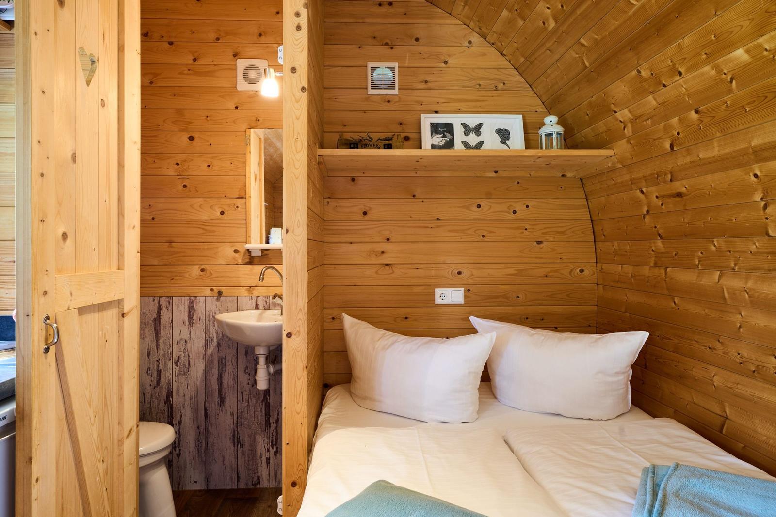 Schlafzimmer mit Bett, Wandregal und integriertem Badezimmer.