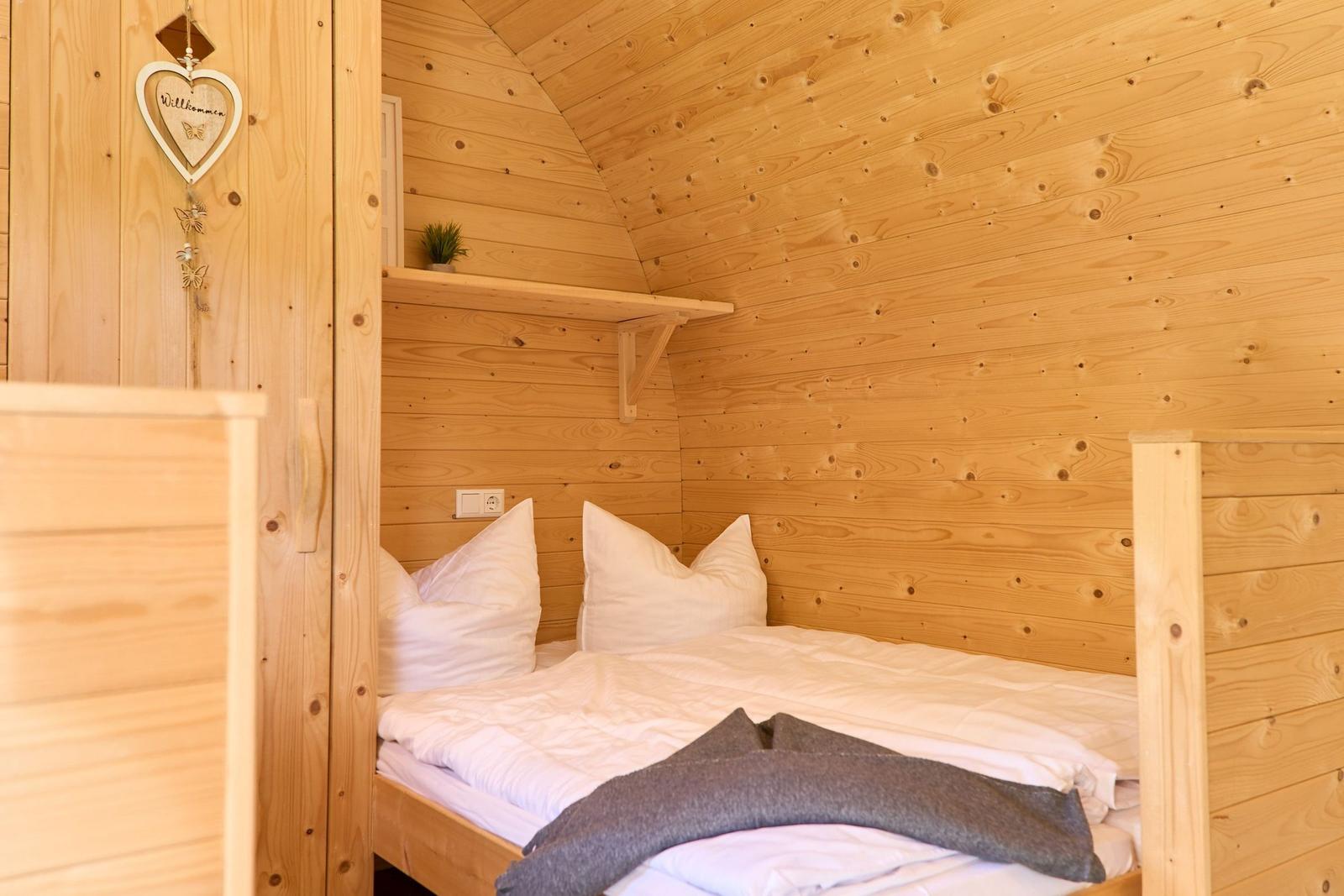 Schlafzimmer mit Holzwand und Bett mit weißen Kissen.