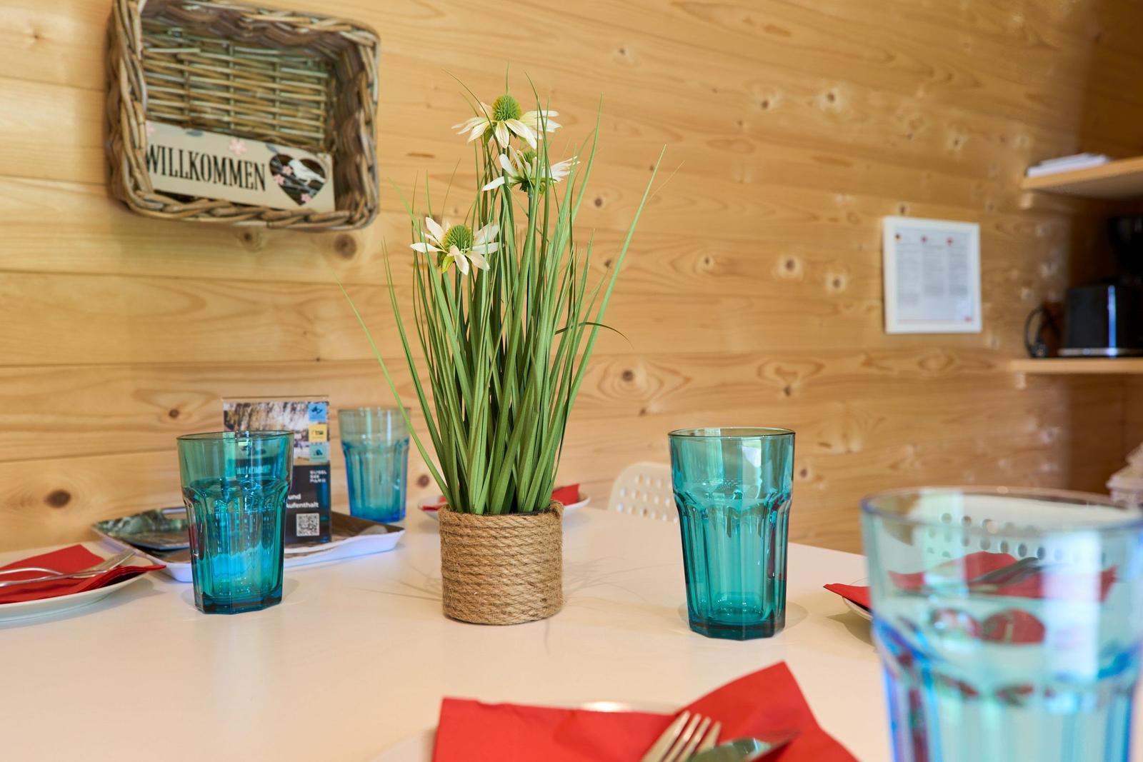 Tisch mit Blumen, Gläsern und roten Servietten in rustikaler Holzwand