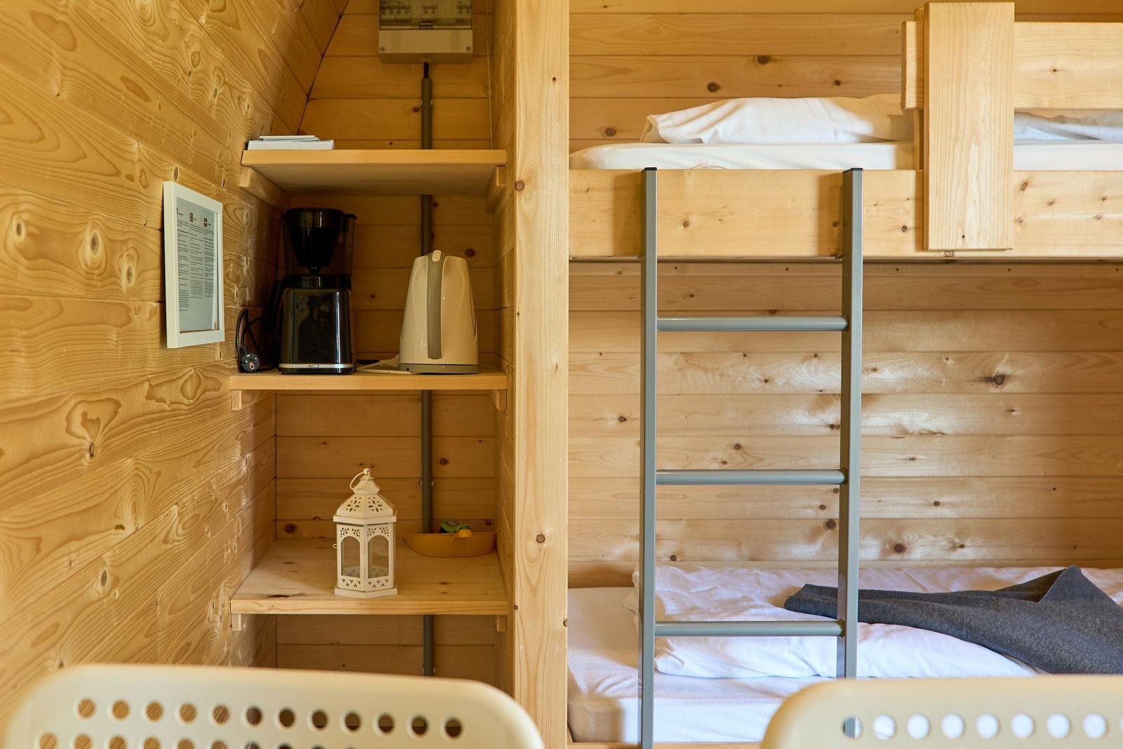 Hochbett mit Leiter und Küchenzeile mit Kaffeemaschine und Wasserkocher.