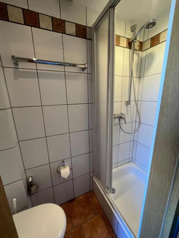 Badezimmer mit Dusche, Toilette und Handtuchhalter.