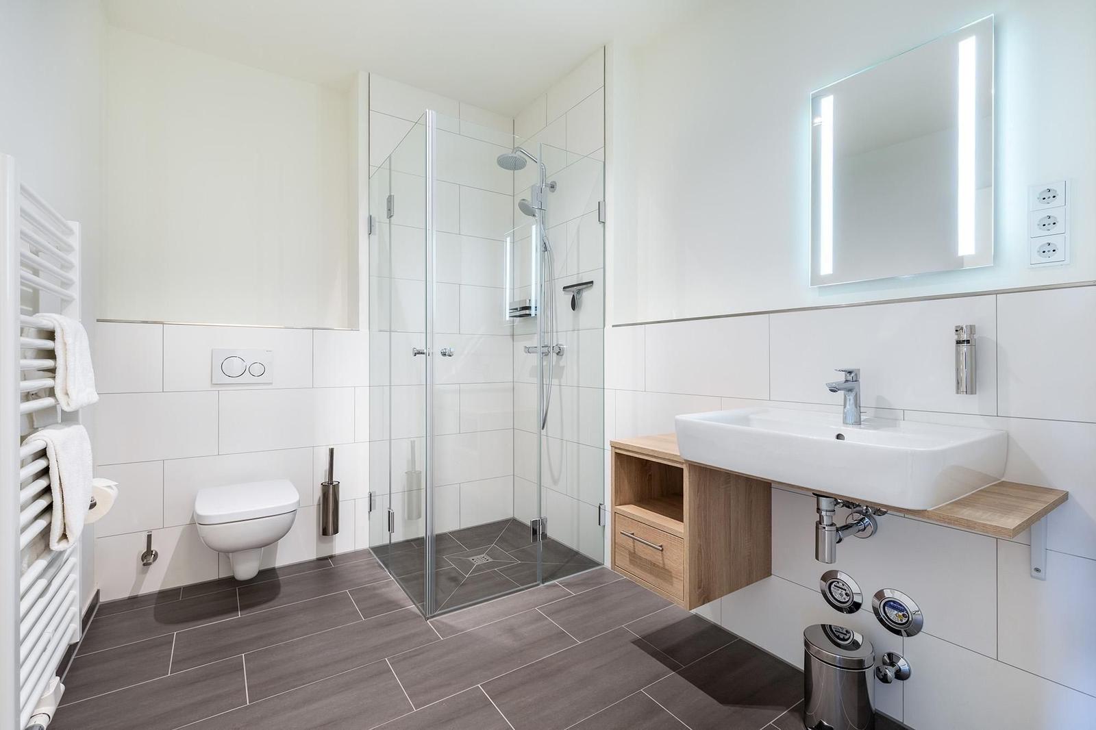 Badezimmer mit Dusche, Waschbecken und Toilette.