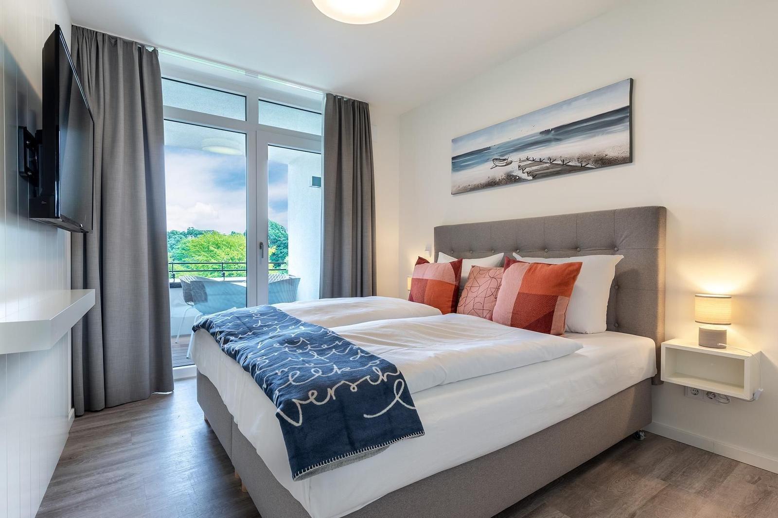 Schlafzimmer mit Doppelbett, Balkon und Wandbild.