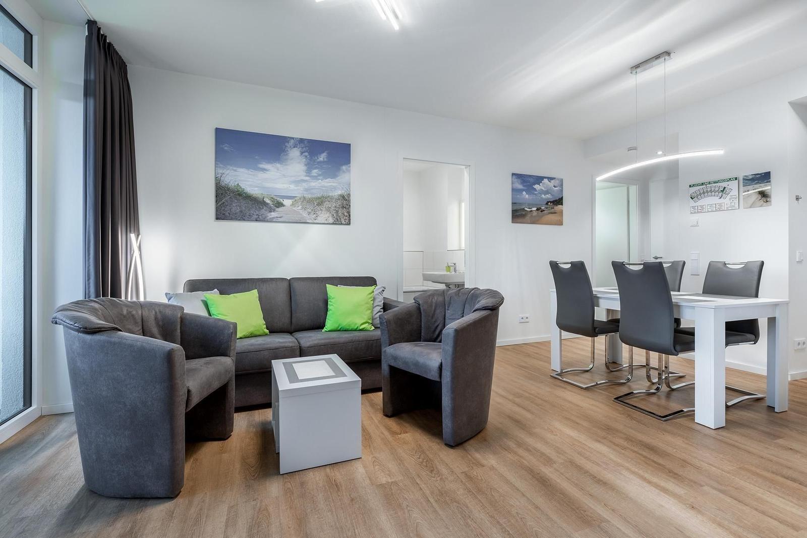 Wohn- und Essbereich mit Sofa, Stühlen und Wandbildern.