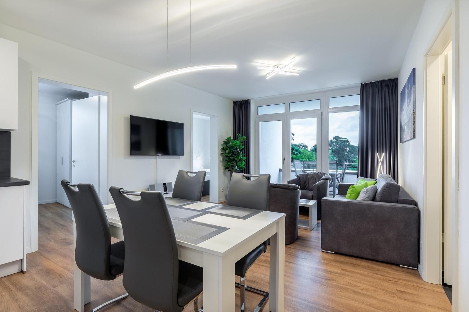 Essbereich mit Tisch und Stühlen, Wohnbereich mit Sofa und Fernseher.