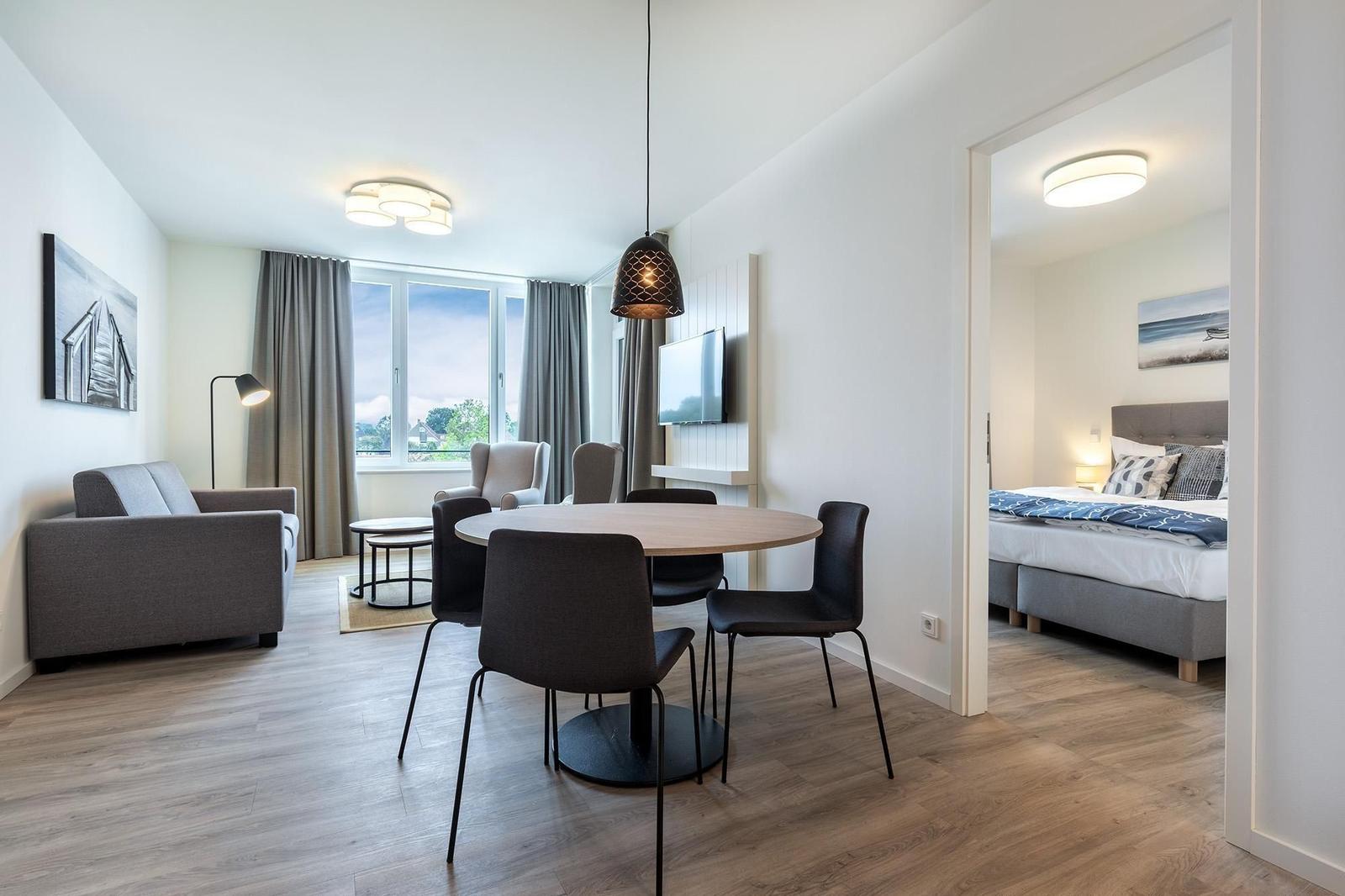 Wohnbereich mit Esstisch, Sofa und Schlafzimmer mit Bett.