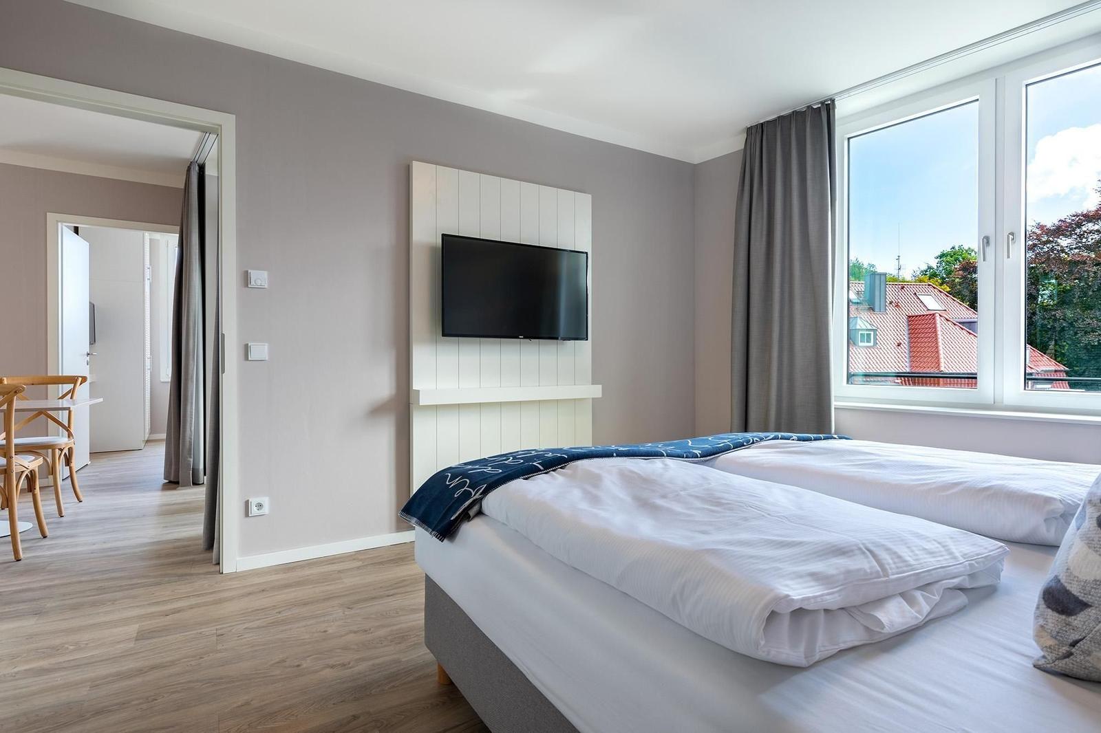 Zwei Betten, TV und Fenster mit Blick auf Dächer.