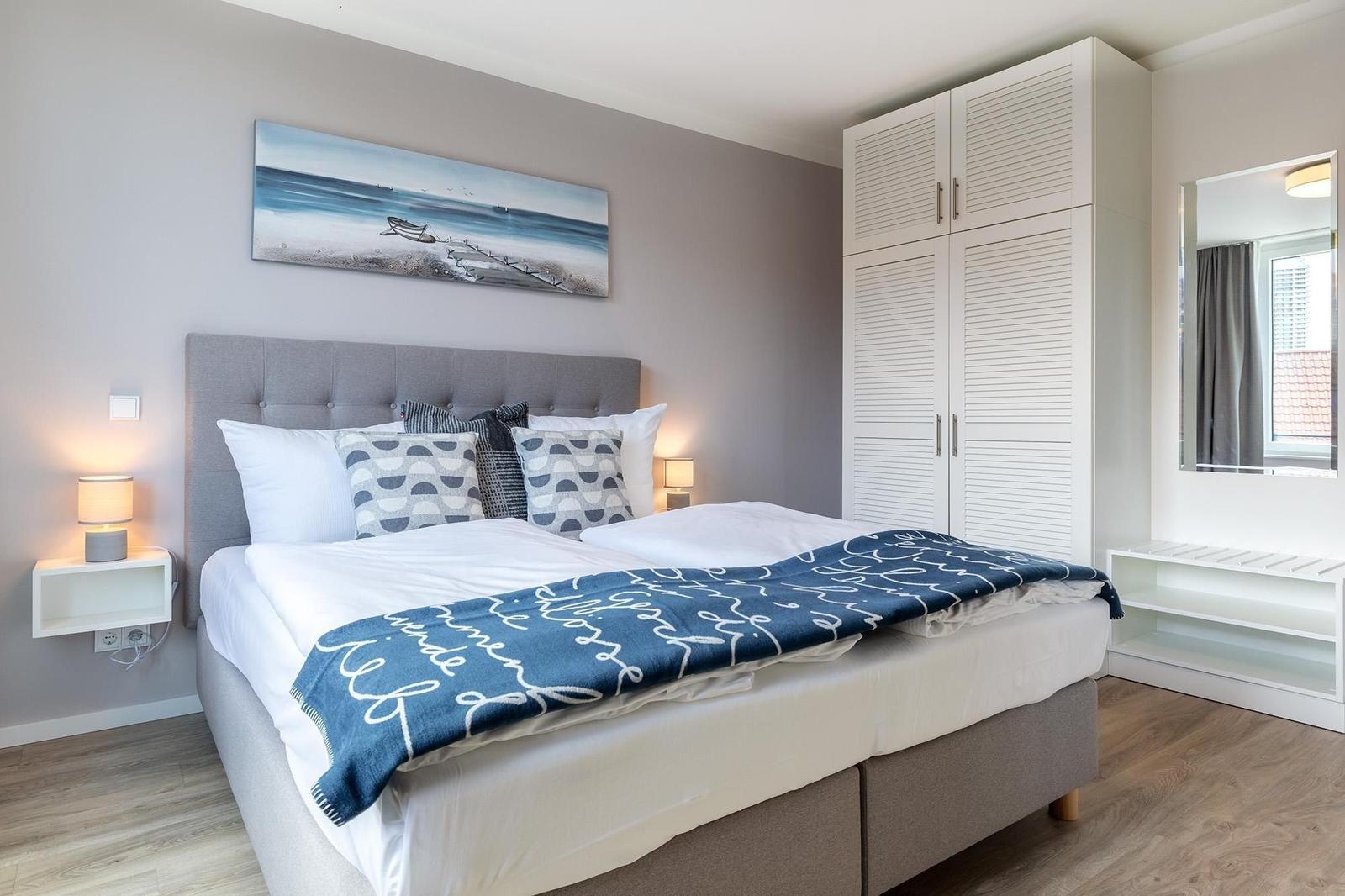 Schlafzimmer mit Bett, Kleiderschrank und Wandbild.