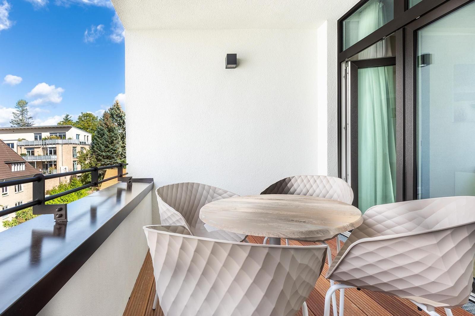 Terrasse mit runden Tisch und vier Stühlen. Holzfußboden und Blick auf Wohngebiet.